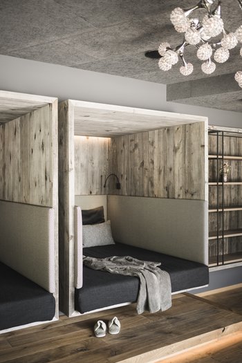 Hotel in the Dolomites for adults only Cozy wooden retreat nook with padding, blanket, and slippers on wooden floor