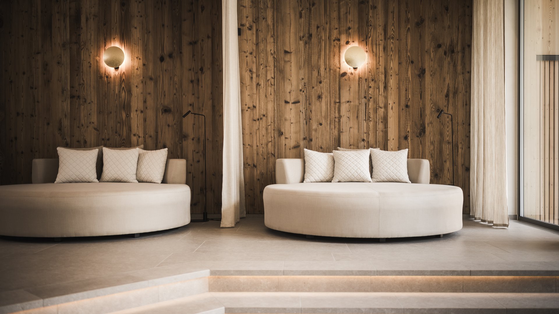 Wellness hotel in South Tyrol | Dolomites Modern lounge with two round sofas and wooden paneled wall