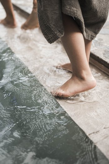 Familienurlaub in den Dolomiten – Natur, Erholung & Abenteuer Kinder waten barfuß am Poolrand im flachen Wasser