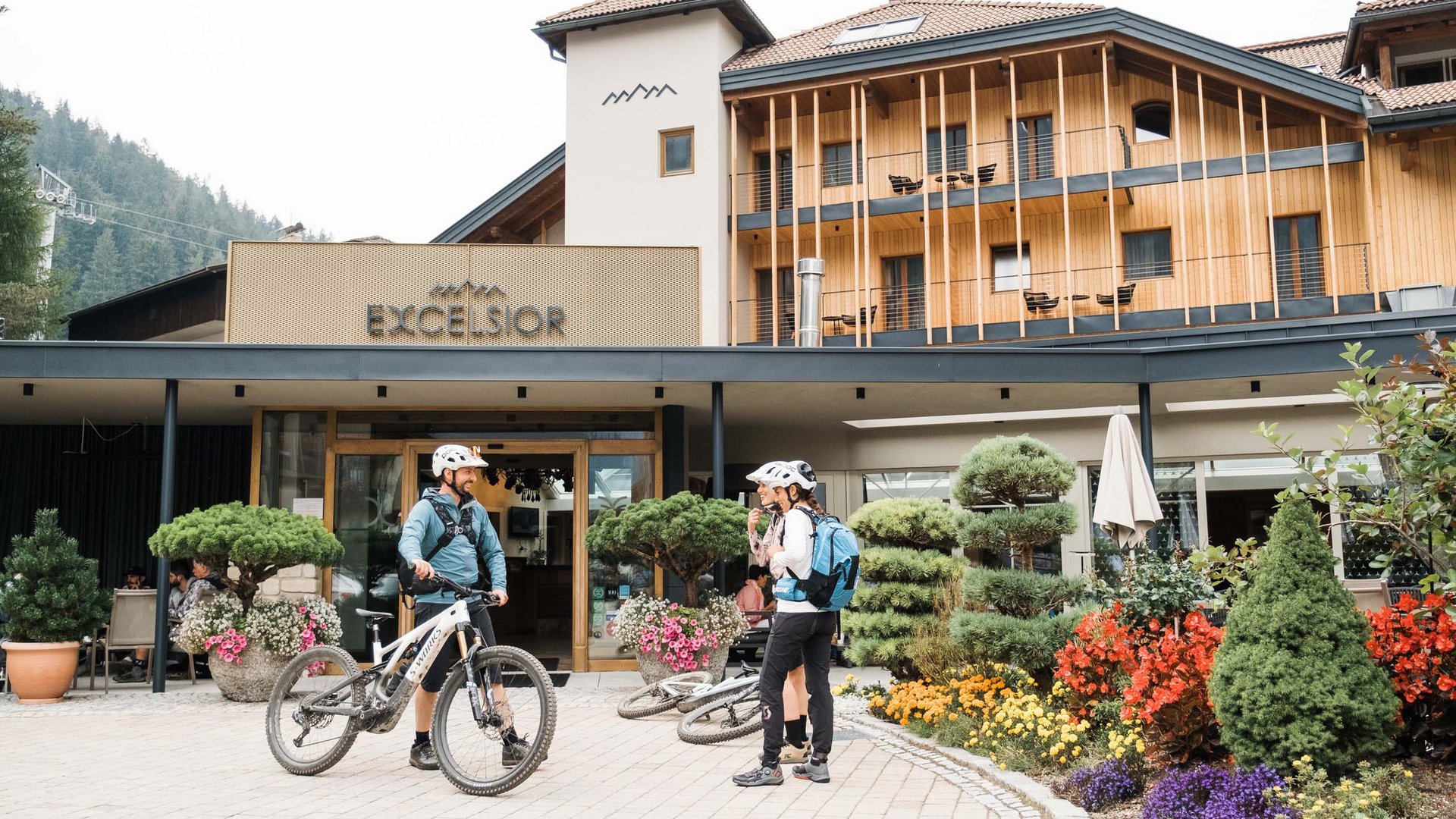 Excelsior: noleggio bici a San Vigilio di Marebbe Due ciclisti in abbigliamento sportivo parlano davanti all'hotel Excelsior