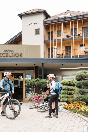 Hotel in South Tyrol with guided hikes Two cyclists in sportswear talking in front of the Excelsior hotel