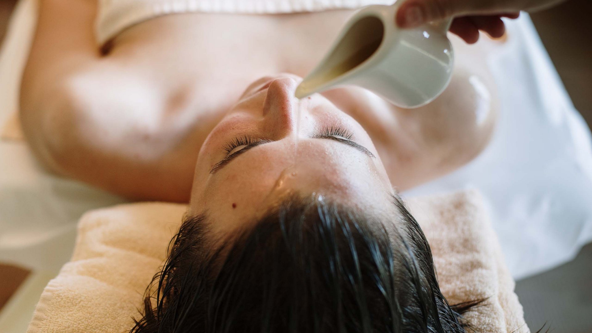 Massaggi e trattamenti nella nostraspa in Alto Adige Donna durante trattamento spa con acqua versata sul viso