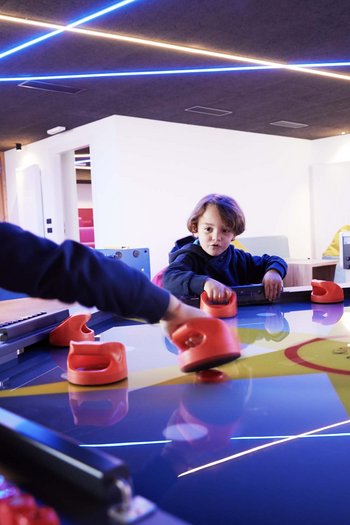 Excelsior: hotel wellness in Alto Adige per famiglie Tre bambini giocano a air hockey a un tavolo illuminato all'interno
