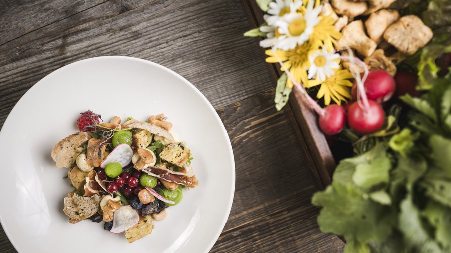 The gourmet hotel in South Tyrol Light vegetable salad with nuts, berries, and herbs on white plate