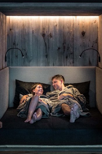 Wellnesshotel in den Dolomiten Paar entspannt zusammen in einem modernen Ruhezonen-Sitzbereich im Spa