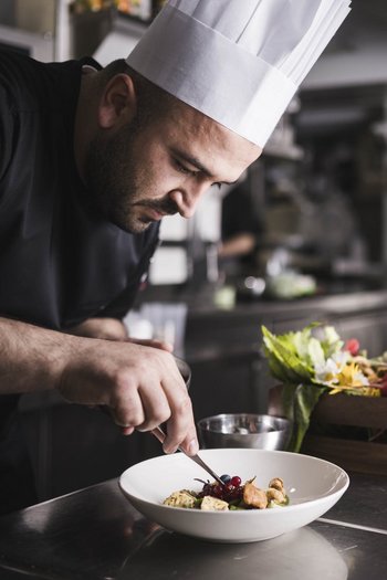Das Gourmethotel in Südtirol Koch richtet Speise mit Garnierung in professioneller Küche an