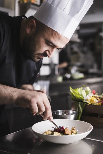 Il vostro hotel gourmet in Alto Adige Cuoco che decora un piatto in una cucina professionale