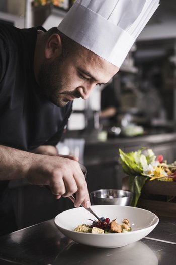 The gourmet hotel in South Tyrol Chef garnishing a dish in a professional kitchen