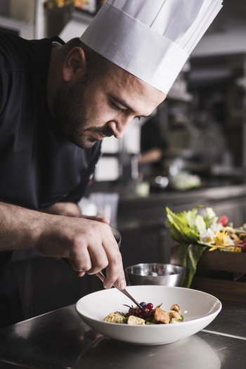 Das Gourmethotel in Südtirol Koch richtet Speise mit Garnierung in professioneller Küche an