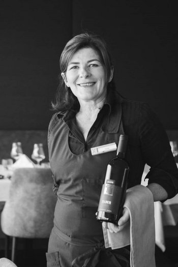Benvenuti nel vostro hotel al Plan de Corones! Cameriera con una bottiglia di vino in un ristorante elegante