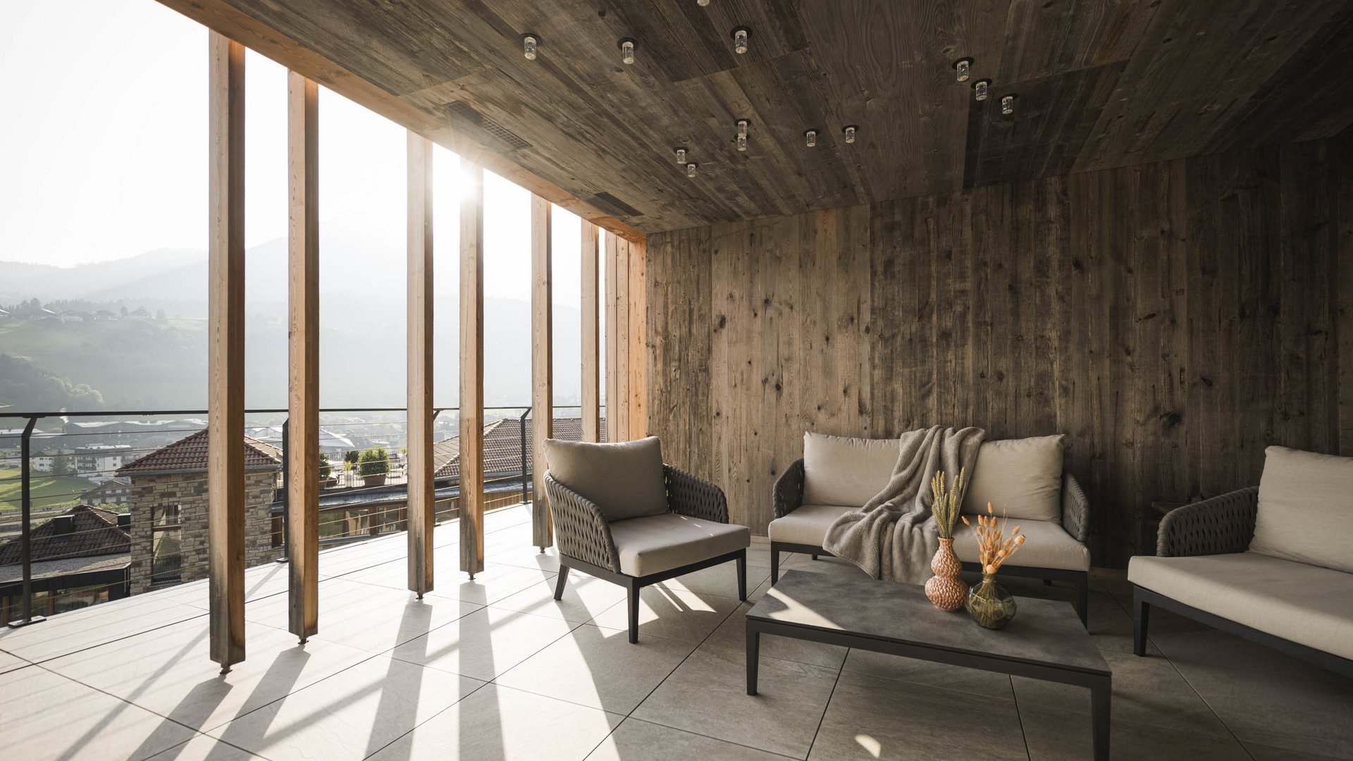 Hotel adults only in Alto Adige: l’Excelsior! Terrazza accogliente con rivestimenti in legno e mobili moderni al pomeriggio