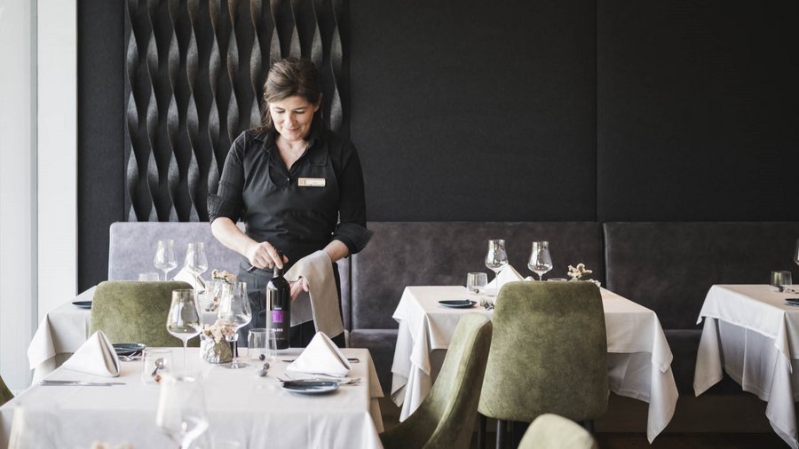 Ihr Hotel in St. Vigil in Enneberg! Kellnerin öffnet eine Weinflasche in einem eleganten Restaurant