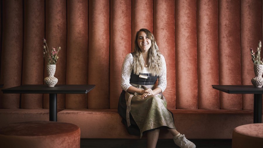 Ihr Hotel in St. Vigil in Enneberg! Frau in traditioneller bayerischer Tracht sitzt vor braunen Möbeln
