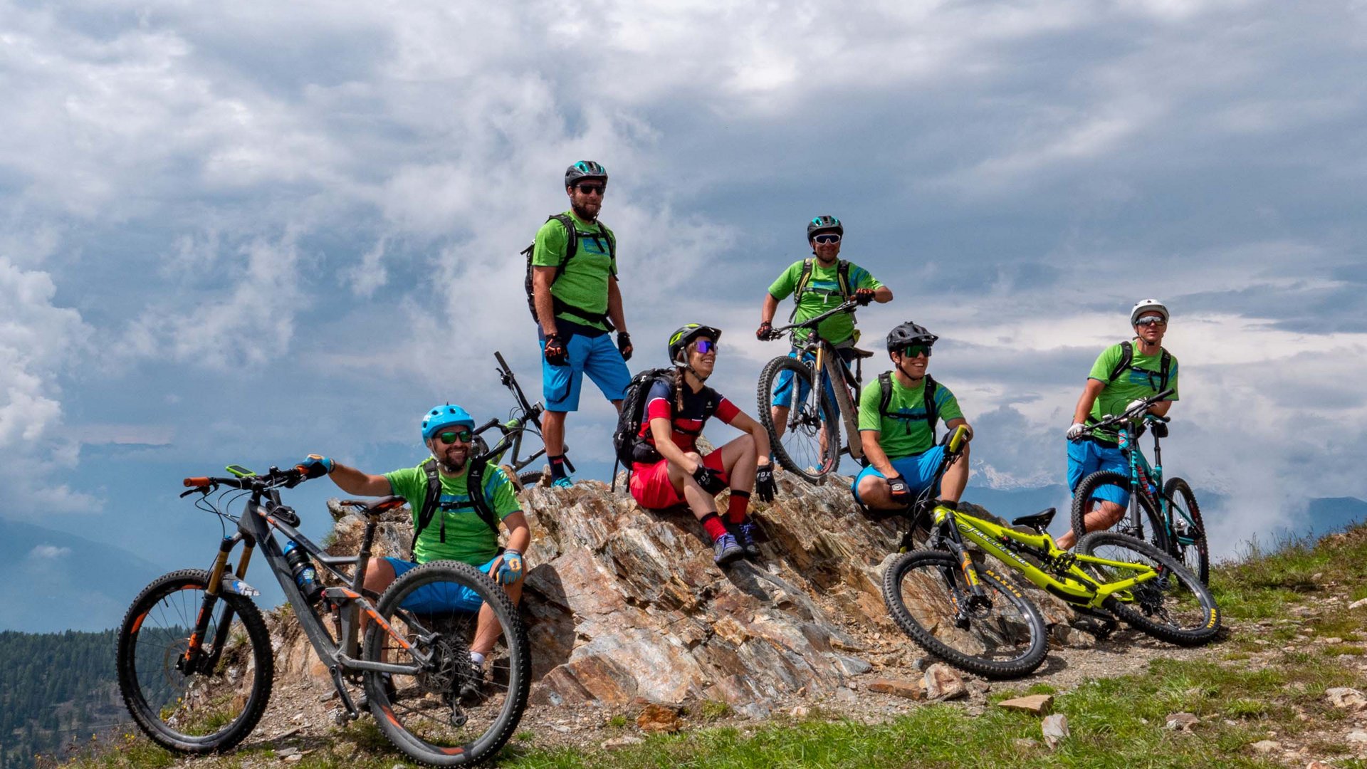 Bike-Verleih Sechs Mountainbiker machen Pause auf einem Felsen mit Fahrrad im Berggebiet