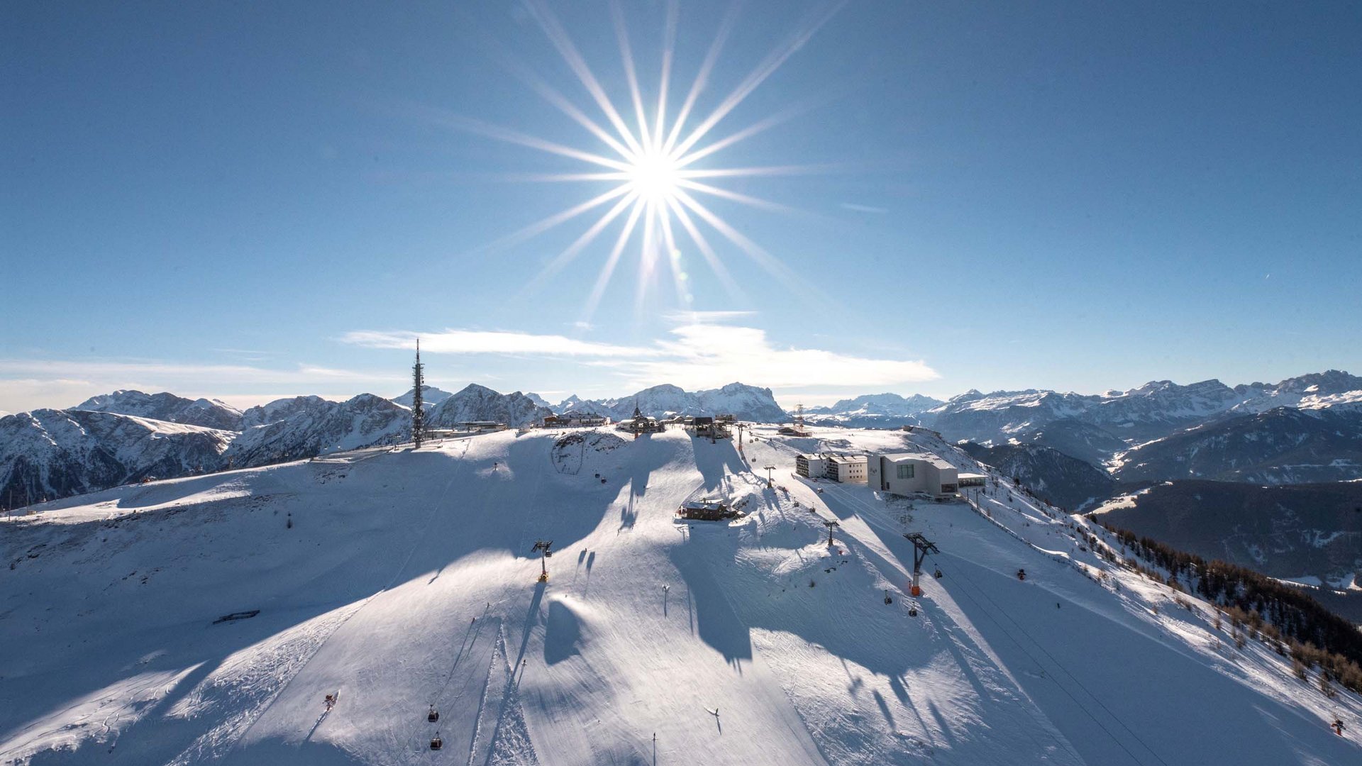 Winterwandern in den Dolomiten rund um das Excelsior Sonniger verschneiter Berggipfel mit Skilift und funktionsgebäuden