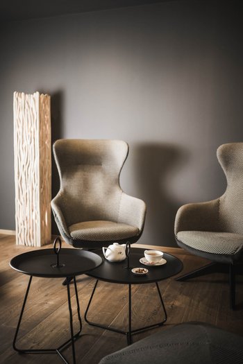 Hotel con infinity pool in Alto Adige: l’Excelsior Area salotto moderna con due poltrone, due tavoli neri e servizio da tè