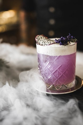 More than a hotel: Excelsior Purple cocktail with foam and fruit on a tray with smoke