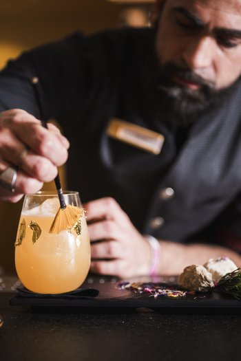 More than a hotel: Excelsior Bartender decorates a cocktail with a brush and gold leaf