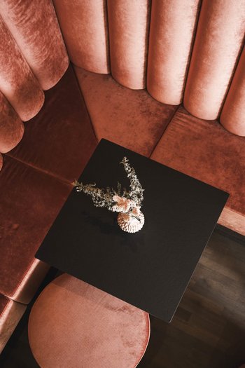 Molto più di un hotel a San Vigilio di Marebbe! Divanetto angolare in velluto rosso con tavolo nero e decorazione floreale visto dall'alto