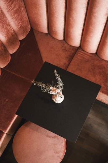 More than a hotel: Excelsior Red velvet corner bench with black table and floral decoration viewed from above