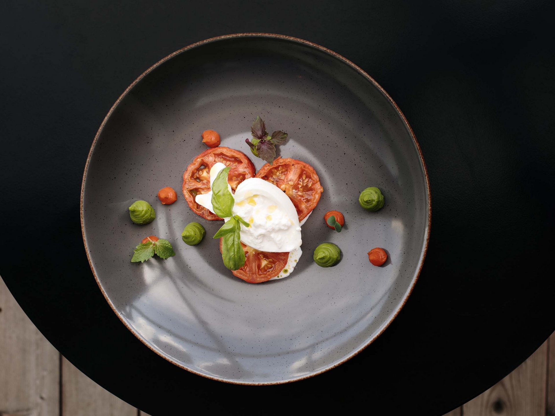 Hotel per celiaci Piatto gourmet con burrata, fette di pomodoro e ciuffi di salsa verde e rossa