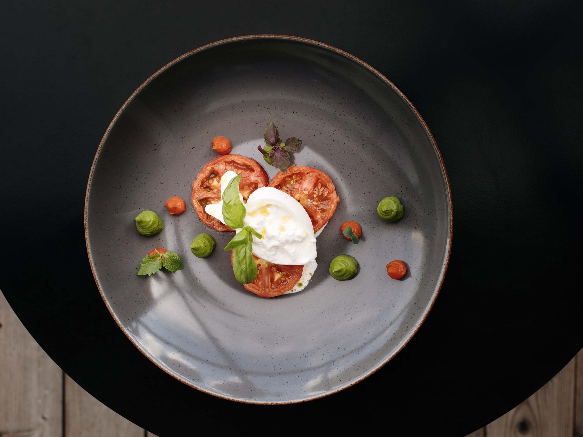 Hotel per celiaci Piatto gourmet con burrata, fette di pomodoro e ciuffi di salsa verde e rossa