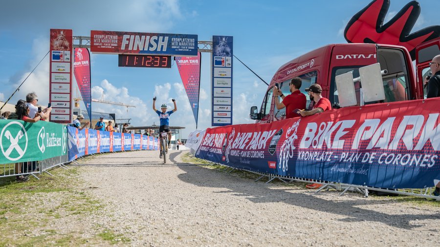 Bike region Cyclist crosses finish line at Kronplatzking MTB Marathon under blue sky