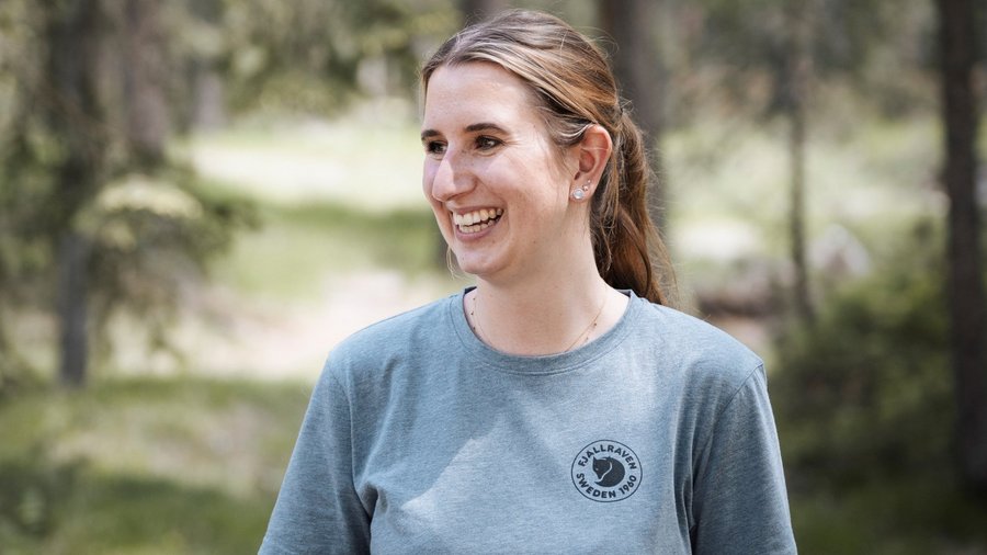 Dolomiten-Hotel für Bergmenschen Lächelnde Frau in grauem Fjällräven T-Shirt im Wald