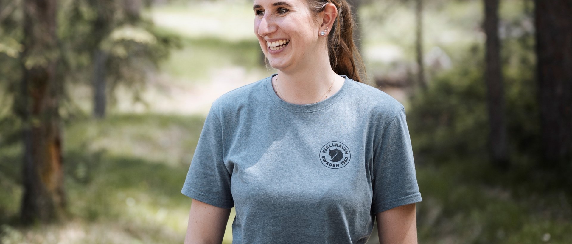 #myexcelsior Sunday News 23.08.2026 Lächelnde Frau in grauem Fjällräven T-Shirt im Wald