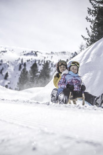 Around the hotel on the slopes in South Tyrol Two kids sledding together on a snowy mountain