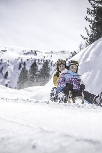 Around the hotel on the slopes in South Tyrol Two kids sledding together on a snowy mountain