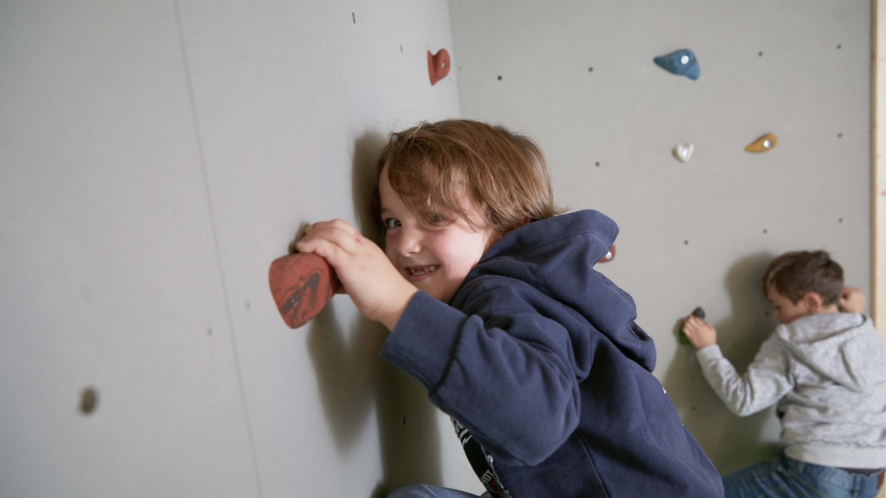 Family-friendly hotel in South Tyrol Two children climbing a wall with colorful climbing holds