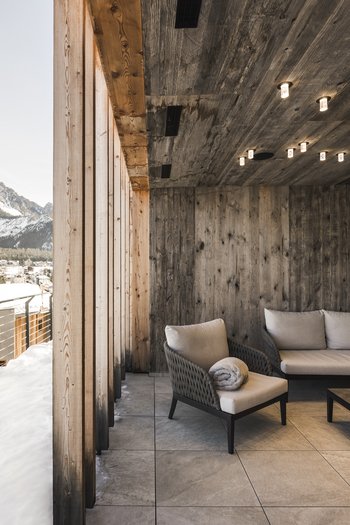 South Tyrol: wellness holiday à la Excelsior Cozy terrace with sofas and snowy mountain view in alpine village