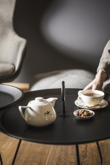 Hotel in den Dolomiten für adults only Teekanne, Tasse mit Tee und Nüsse auf schwarzem Tisch in gemütlichem Raum