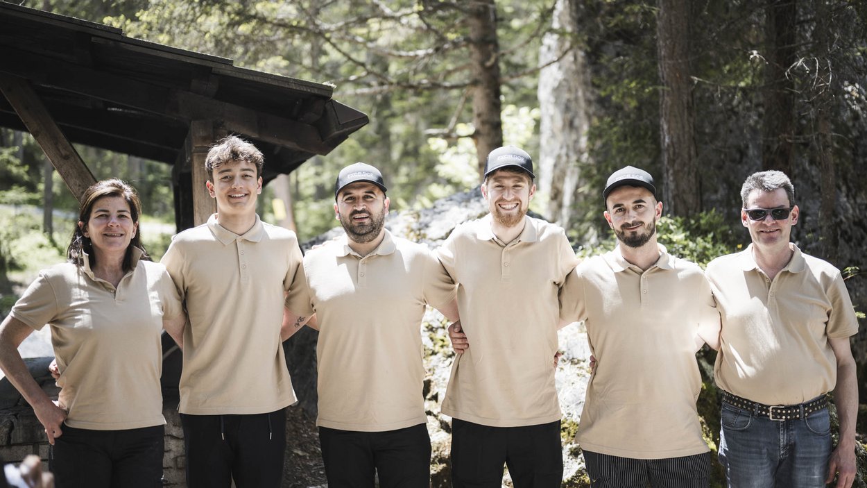 Sustainable hotels in South Tyrol? The Excelsior! Six people in beige polo shirts standing outdoors with arms around each other