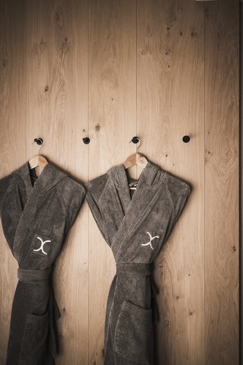 Wellness hotel in South Tyrol | Dolomites Two gray bathrobes hanging on hooks on a wooden wall