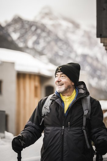 Hotel am Kronplatz direkt an der Piste Älterer Mann in Winterkleidung mit Wanderstock in Berglandschaft
