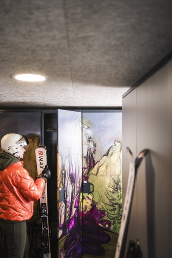 Hotel at Plan de Corones/Kronplatz on the slopes Person with skis and helmet standing by a colorful ski locker in ski room