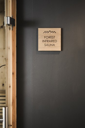 Hotel in the Dolomites for adults only Entrance to forest infrared sauna with wooden door and decorative wooden sticks