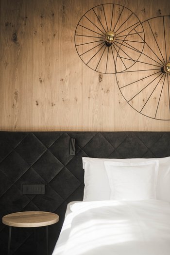 Excelsior: Wanderhotel in den Dolomiten Modernes Schlafzimmer mit Holzwand und schwarzem gepolstertem Kopfteil