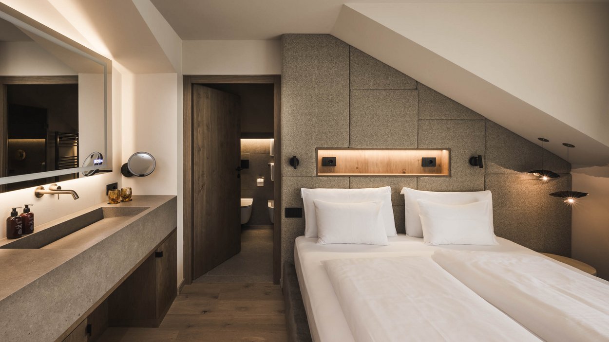 Sustainable hotels in South Tyrol? The Excelsior! Modern bedroom with double bed, built-in sink, and open bathroom