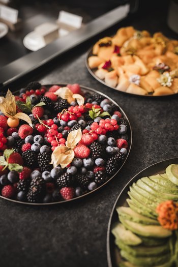 Il vostro hotel gourmet in Alto Adige Varie bacche su un piatto, accanto a fette di melone e avocado