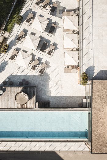 Wellnesshotel in den Dolomiten Drohnenaufnahme eines Pools mit Sonnenschirmen und Liegestühlen auf der Terrasse