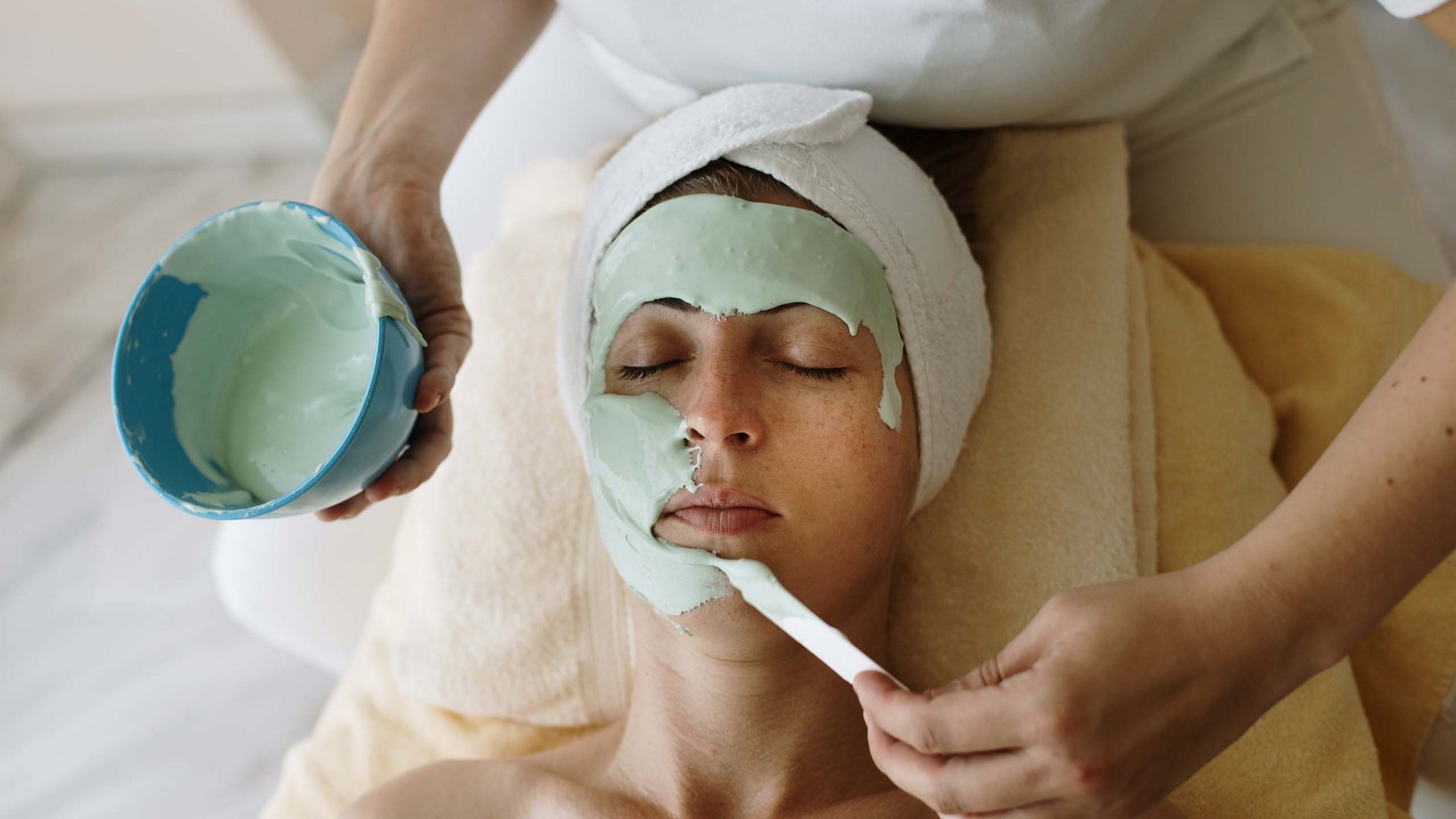 Donna che riceve una maschera facciale durante un trattamento spa