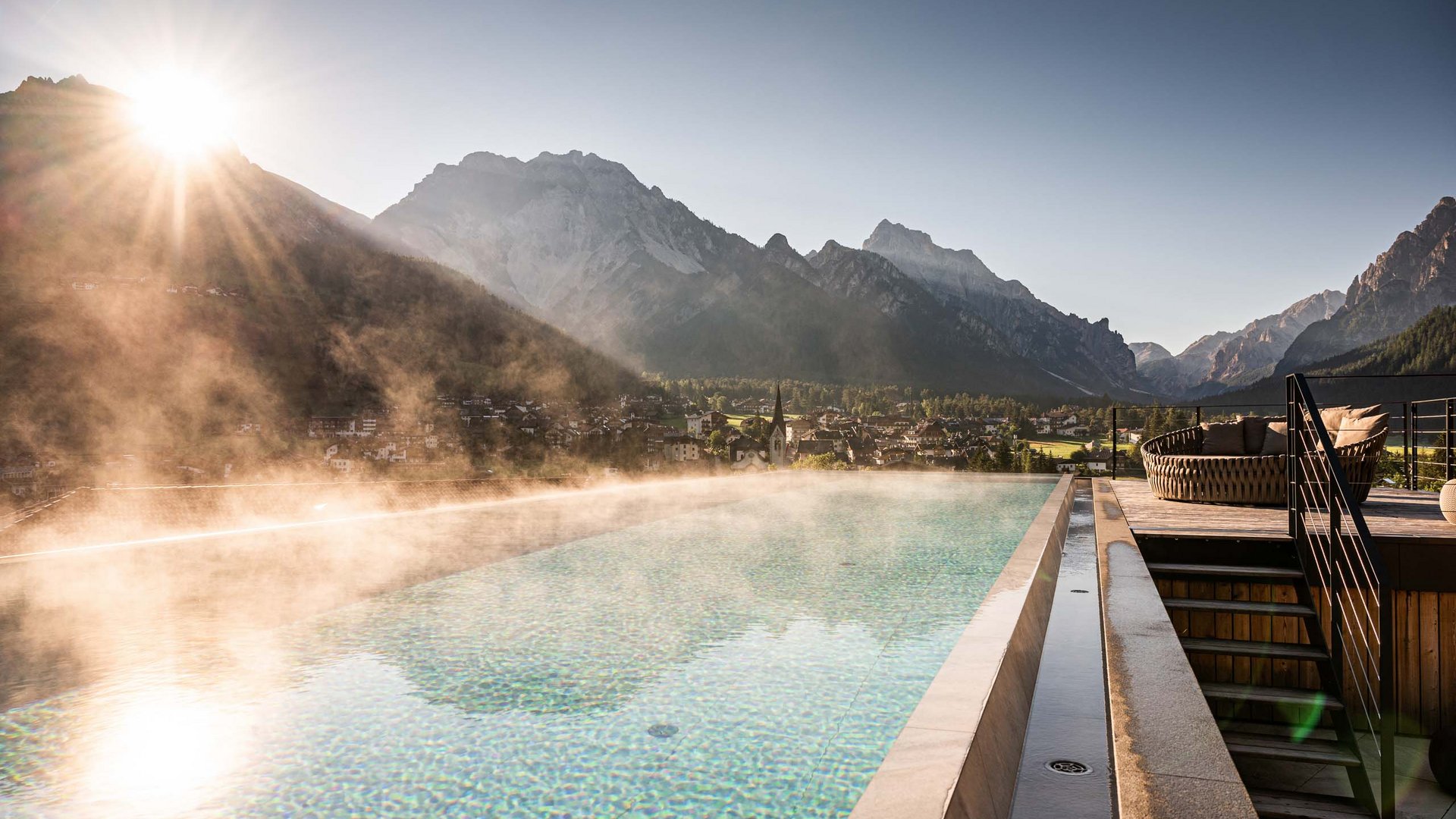 Luxushotel in den Dolomiten | Excelsior in St. Vigil Infinity-Pool mit Bergblick bei Sonnenaufgang und Nebel über den Alpen