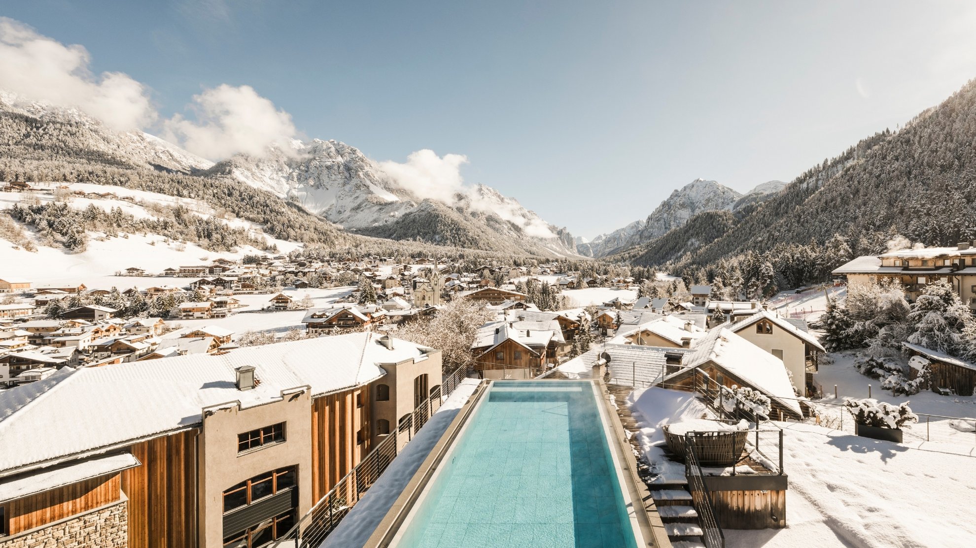 Offers: wellness and hiking | South Tyrol Long outdoor pool overlooking a snow-covered village and snowy mountains