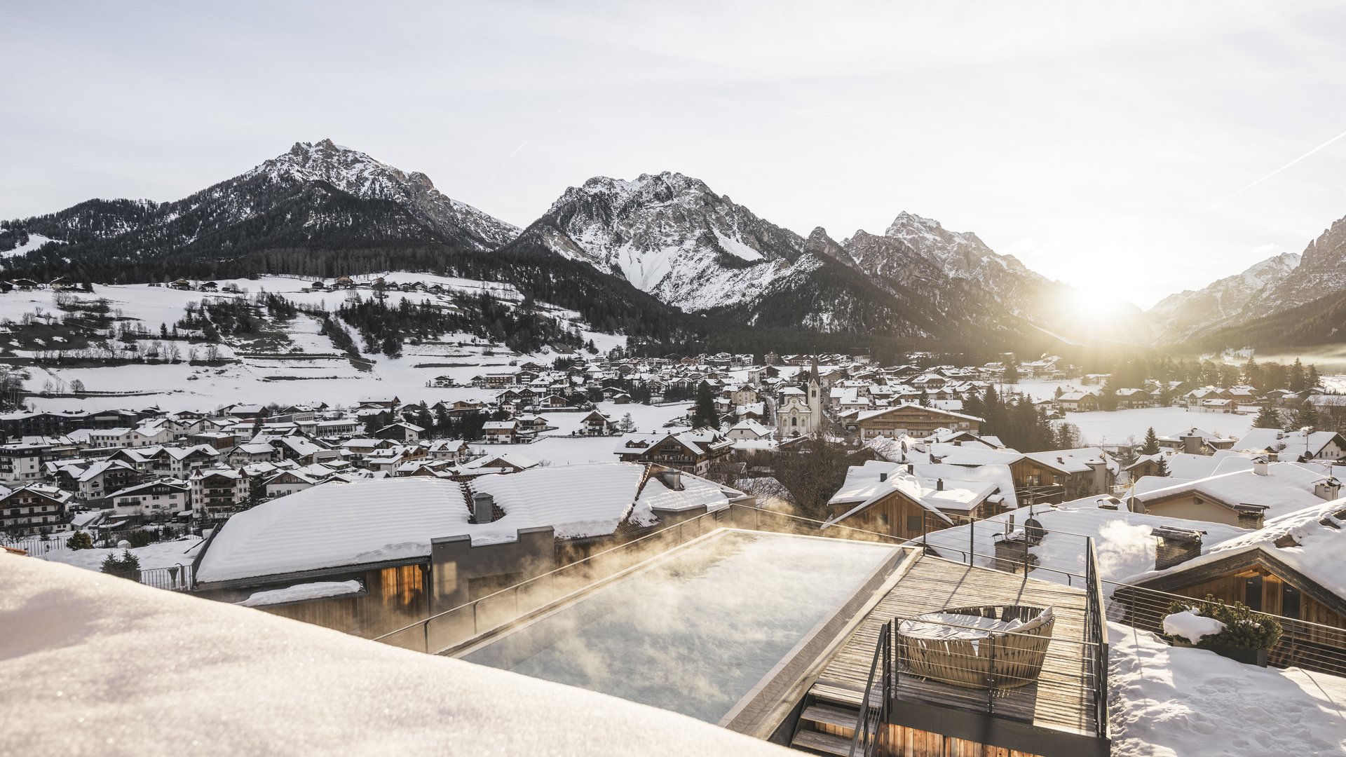 Hotel in the Dolomites for adults only Sunrise over snowy mountain village with heated outdoor pool