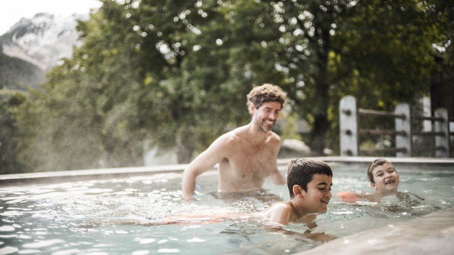 Excelsior: hotel wellness in Alto Adige per famiglie Uomo e due bambini che si divertono nuotando in una piscina all'aperto