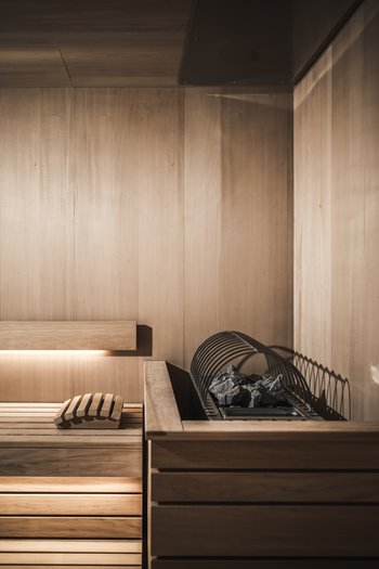 Le nostre novità 2024 Interno sauna moderno con rivestimento in legno e pietre riscaldanti