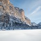Schneebedeckte Berglandschaft mit Tannen und Hütten unter klarem Himmel
